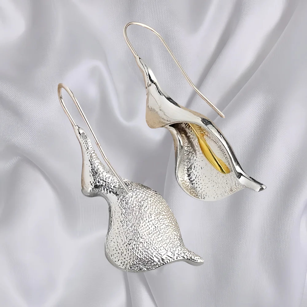 Silver and gold calla lily earrings on a satin background