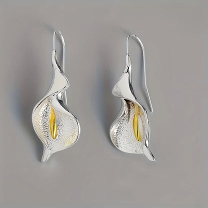 Silver earrings with gold accents on a gray background